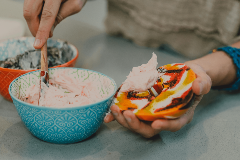 A close-up of a creamy scoop of Journeyman Ice Cream in a waffle cone, topped with sprinkles and drizzled with chocolate sauce, showcasing its rich texture and artisanal quality.
